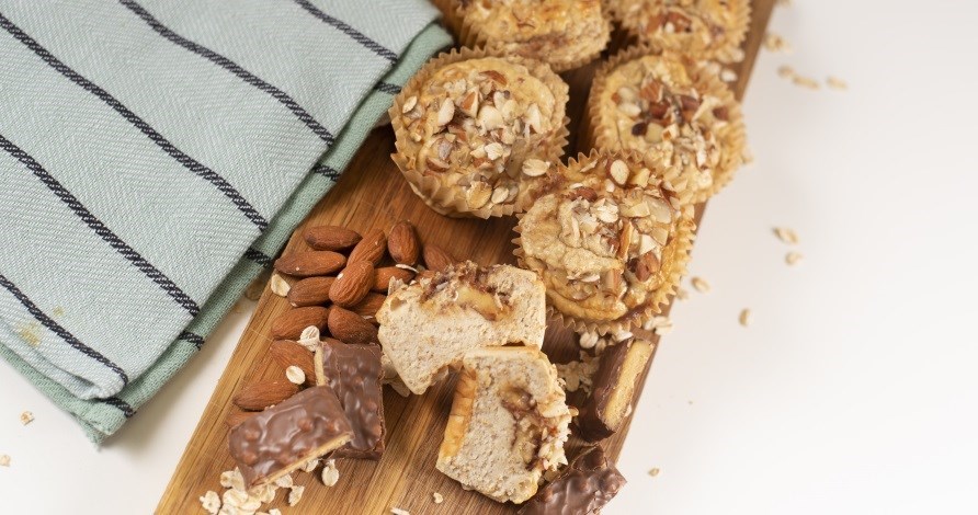 Bild p proteinmuffins uppdukade p en skrbrda med mandlar och Core PROBAR.